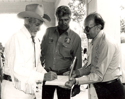 Guy Madison signs an autograph for a fan at the Golden Boot Awards in 1986. Jim Roberts of Mississippi, who for years sponsored the annual Pre-Boot party at Sportsmen’s Lodge on Ventura Blvd. in Studio City, CA, is in the middle.