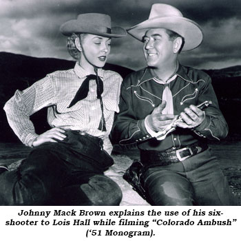 Johnny Mack Brown explains the use of his six-shooter to Lois Hall while filming "Colorado Ambush" ('51 Monogram).