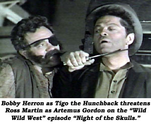 Bobby Herron as Tigo the Hunchback threatens Ross Martin as Artemus Gordon on the "Wild Wild West" episode "Night of the Skulls".