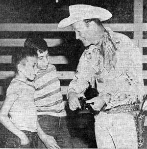 Above three photos taken during Roy Rogers’ appearance in early October 1957 for the New Mexico State Fair in Albuquerque. Top photo, Roy signs an autograph for 14 year old Janet Latsha. In the second photo Roy displays one of his guns for two members of a family of ten orphaned earlier in the year, Eddie and Gregory Chavez. In the third photo Roy shakes hands with children at the State Fair Coliseum.