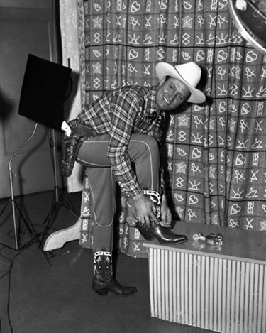 Gene Autry puts on his spurs for a photo shoot. (Thanx to Billy Holcomb.)