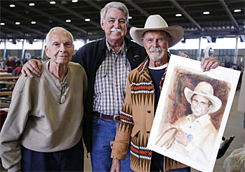 “Gunsmoke”—Buck Taylor holds up his self portrait for two buyers. 