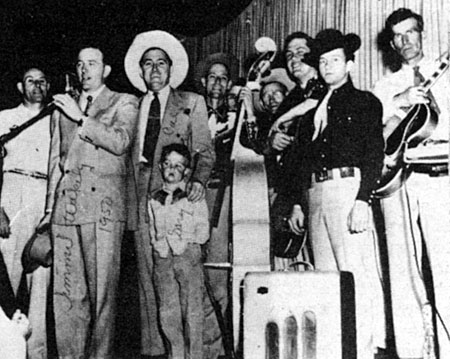 Cal Shrum (white hat, center) and son Gary welcome guest star Jimmy Wakely to Shrum’s Saturday night show which in the ‘50s originated in Albuquerque, New Mexico. 