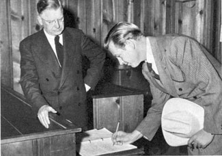 Rex Allen signs the guest roster for Rev. John Wells at the 
Little Brown Church in the Valley.