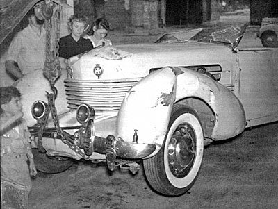 The 1937 Cord 812 Phaeton car in which Tom Mix was killed shown here still hooked to the tow truck that brought it in to Florence, Arizona. 