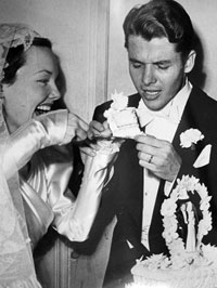 At their wedding, new wife Wanda Hendrix cuts a piece of cake for Audie Murphy.