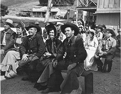 Johnny Carpenter (third from left) and stuntman Lou Roberson (right) (Chuck Roberson’s brother) prepare to watch entertainer Texas Rose Bascomb during a scene for “Lawless Rider” (‘54). The girl between them is unknown. 