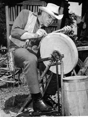 Lorne Greene puts his nose to the grindstone as he sharpens the sight on his .45. 