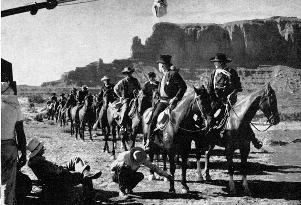 John Ford (seated) directs a sheriff’s posse scene with Ward Bond and John Wayne in the lead for “The Searchers”.