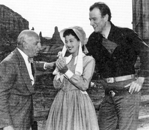 On location for “Angel and the Badman”, Republic president Herbet J. Yates and star John Wayne look on as Gail Russell cuddles a baby duckling.