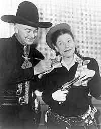 Hopalong Cassidy signs an autograph for Judy Canova. 