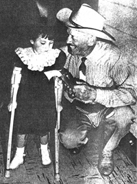 Tom London shows his six-shooter to four-year-old Shirley at a telethon for crippled children in Yuma, AZ in August 1957. 
