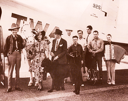 Tex Ritter has just landed in Hollywood in 1936 to begin work on his first Western, “Song of the Gringo”. He’s met by (L-R) leading lady Joan Woodbury, writer/director John McCarthy (with dog), Cactus Mack (with white hat), Glenn Strange (tall man in back), and four unidentified musicians. 