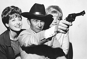 “The Virginian”, James Drury, takes aim in Essendon Airport in Melbourne, Australia with Australian TV personalities Panda and singer Val Ruff. 