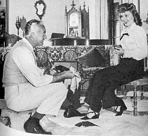 William “Hopalong Cassidy” Boyd polishes his guns in his living room with attentive wife Grace Bradley. 