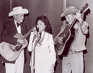 Ray Whitley and Eddie Dean accompany an unknown songstress. 