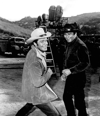 Clowning around in between scenes, Doug McClure mugs for the camera with James Drury on "The Virginian". Note the cigarette in Drury's right hand. 