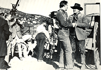 While making "Stagecoach", director John Ford checks out a shot through the viewer of John Wayne and George Bancroft. 