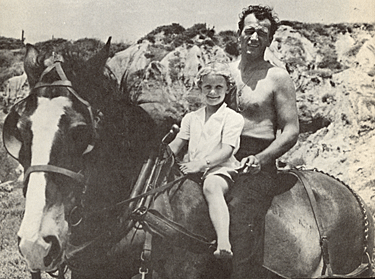 John Wayne with director Joe Kane’s daughter, Louise, on location during the making of Republic’s “Flame of the Barbary Coast” in 1945.