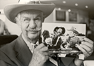 At a Western film festival sidekick Slim Andrews holds up a vintage 
picture of he and Tex Ritter. 