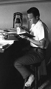 A barefooted Eric Fleming ("Rawhide") does a little research at home. 