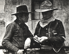 William S. Hart shows the colt he thinks was owed by Billy the Kid to Johnny Mack Brown during a break in the 1930 filming of King Vidor's "Billy the Kid". Hart was technical advisor on the film. 
