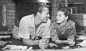 "Laramie's" John Smith and his wife from '60-'64, actress Luana Patten, 
relax by the fireplace. 