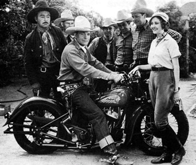 Buck Jones is mighty proud of his new Indian motorcycle. Standing in front is “Red Rider” serial heroine Marion Shilling. Beside her in the checkered shirt is Ed Cobb. Photo taken in 1934 during the making of that Universal serial. (Photo courtesy Bobby Copeland.)