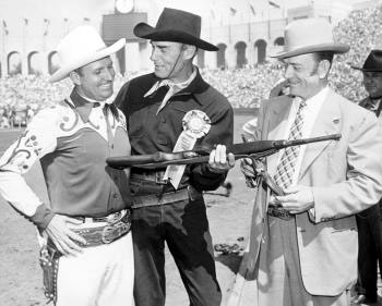 Randolph Scott and an official of the annual Sheriff’s Rodeo at the L. A. Colisseum make a rifle and ribbon presentation to Gene Autry. (Thanx to Bobby Copeland.)