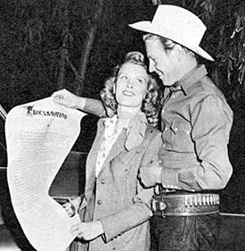 Rex Allen show his wife Bonnie the scroll presented to him in the inaugural ceremony naming him Honorary Mayor of Studio City in 1950.