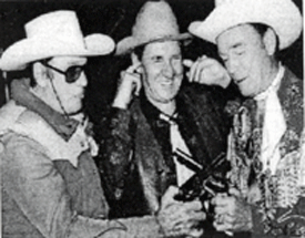 Pat Buttram holds his ears as Clayton Moore and Roy Rogers match guns.