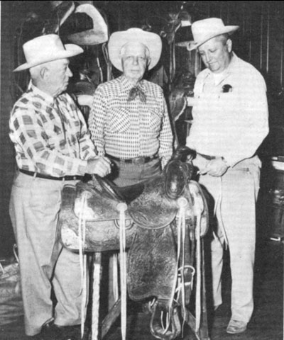 Hoot Gibson, in 1958, with the Hamley Trophy saddle he won as All Around Champion Cowboy at the 1912 Pendleton Round-Up. That was the first time such an award had been up for grabs. Hoot had entered five events, saddle bronc riding and the relay, pony express, roman, and wild horse races. Shown with Hoot are Lester Hamley (left), owner of Hamley and Company and Jack Stangier (right), president of the Pendleton Round-Up.