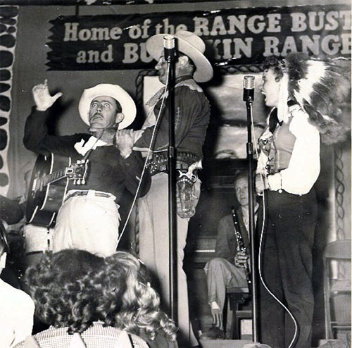 The Broome Brothers (Joe, Lee and Ray) used to be Ray “Crash” Corrigan’s band at Corriganville in the ‘50s. Here Lee Broome does a routine with Crash and his wife Elaine Dupont. Note the sign refers to both Corrigan’s Range Busters and his unsold TV pilot “Buckskin Rangers”. (Photo courtesy Ron Broome.)