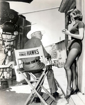 Director Howard Hawks talks with gorgeous Angie Dickinson on the set of “Rio Bravo”.