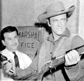 James Arness compares his sixshooter with a new Mauser rifle while on a practice shoot at the Los Angeles Police Academy Pistol Range in 1959.
