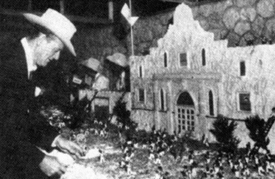 In November 1960 John Wayne slices the first piece of a 30 ft. “The Alamo” premiere cake which recreated the attack of the Alamo.