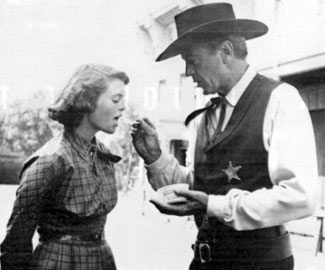 Gary Cooper gives daughter Maria Cooper Janis a bite of his snack on the set of “High Noon” (‘52).