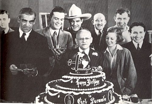 Celebrating Universal honcho Carl Laemmle’s 67th birthday in January 1934 are (l-r) James Scott, Boris Karloff, Hugh Enfield, Ken Maynard, Laemmle, Vince Barnett, Margaret Sullivan, Andy Devine and Carl Laemmle Jr.