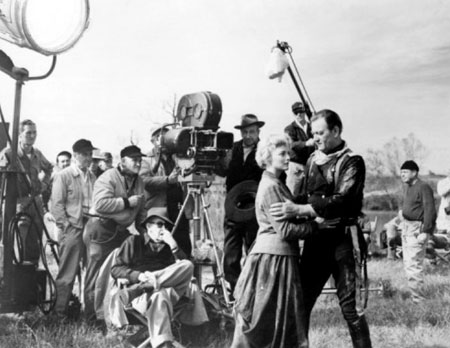John Ford directs a “Horse Soldiers” scene with Constance Towers and John Wayne. Cinematographer William Clothier is behind Ford to the right of the camera.
