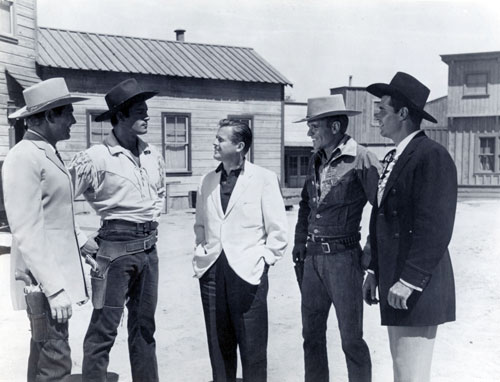 On the Warner Bros. backlot producer Bill Orr (center) talks with Wayde (“Colt .45”) Preston, Clint (“Cheyenne”) Walker, Will (“Sugarfoot”) Hutchins and James (“Maverick”) Garner. (Thanx to Neil Summers.)