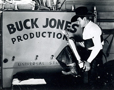 Buck Jones holds a trophy for ?? in front of a Universal Studios sign for his Buck Jones Productions ‘34-‘37.