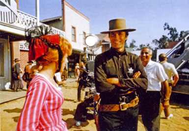 On the Universal backlot, Clint Eastwood shares a joke with actress Arlene Golonka during the filming of “Hang ‘Em High”. That’s director Ted Post approaching the couple.