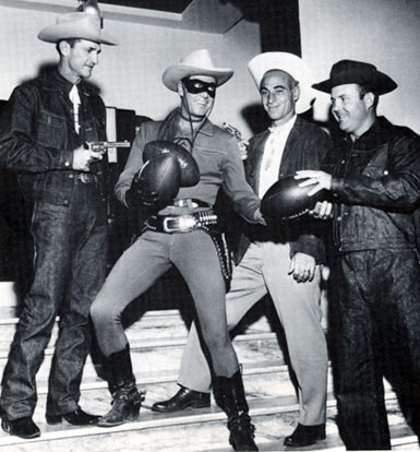 Sammy Baugh (“King of the Texas Rangers”), coach of the Hardin-Simmons University football team in November 1957, holds a gun on Clayton Moore as the Lone Ranger in the Santa Rita, Tucson, AZ, hotel lobby. Assistant coaches Wayne Millner and John Steber are on the right. Baugh and his team were in Tucson to play the University of Arizona and Moore was filming “Lone Ranger and the Lost City of Gold”.