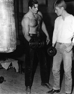 In between working on their Warner Bros. shows, Clint “Cheyenne” Walker instructs Will “Sugarfoot” Hutchins on the proper use of gym weights.