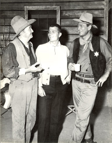 Walter Brennan, Pat Wayne and John Wayne have a chat during a break from filming “Rio Bravo” (‘59 Warner Bros.).