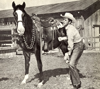 Audie Murphy attends to the hoof of one of his race horses.
