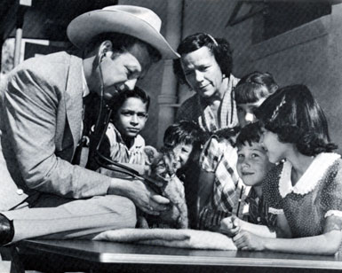 While appearing at the Tucson, AZ, Rodeo in February, 1957, Rex Allen, then starring as TV’s “Frontier Doctor”, examines an eight week old cougar cub from the Arizona-Sonora Desert Museum. Dorothy Jones, Allen’s teacher when he was a boy in Willcox, watches with some of her students from Davis School—Willie Canez, Joe Carmaliche, Sylvia Glass, Jimmy Wilkie and Mary Helen Young.