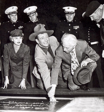 Sid Grauman helps John Wayne put his fist and boot prints into the cement outside Grauman’s Chinese Theater on January 25, 1950. Wayne’s concrete block is made from black cement from the black sands of Iwo Jima.