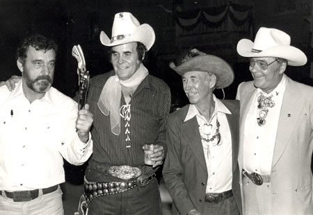 Victor French tries his luck gun handling with Sunset Carson’s .45 as Eddie Dean and Monte Hale look on during a tribute to Vera Ralston at CBS studios in Studio City, CA. (Thanx to Neil Summers.)