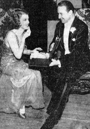 Monte Blue, featured in many Westerns from the silent era on through early television, assists Jeanette McDonald with her makeup before their act went on at the 1931 annual Christmas benefit show at the Shrine Civic Auditorium in L.A.